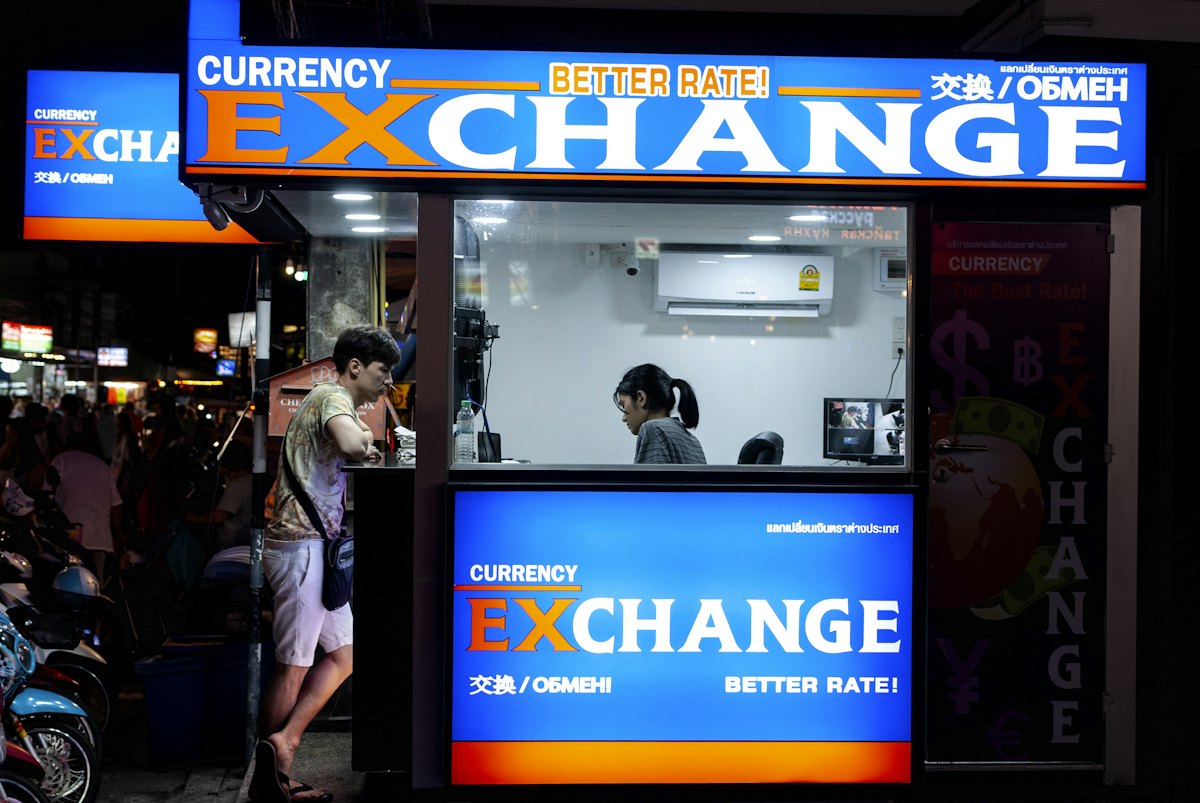 A street currency exchange booth with a Better Rate sign at night in Thailand