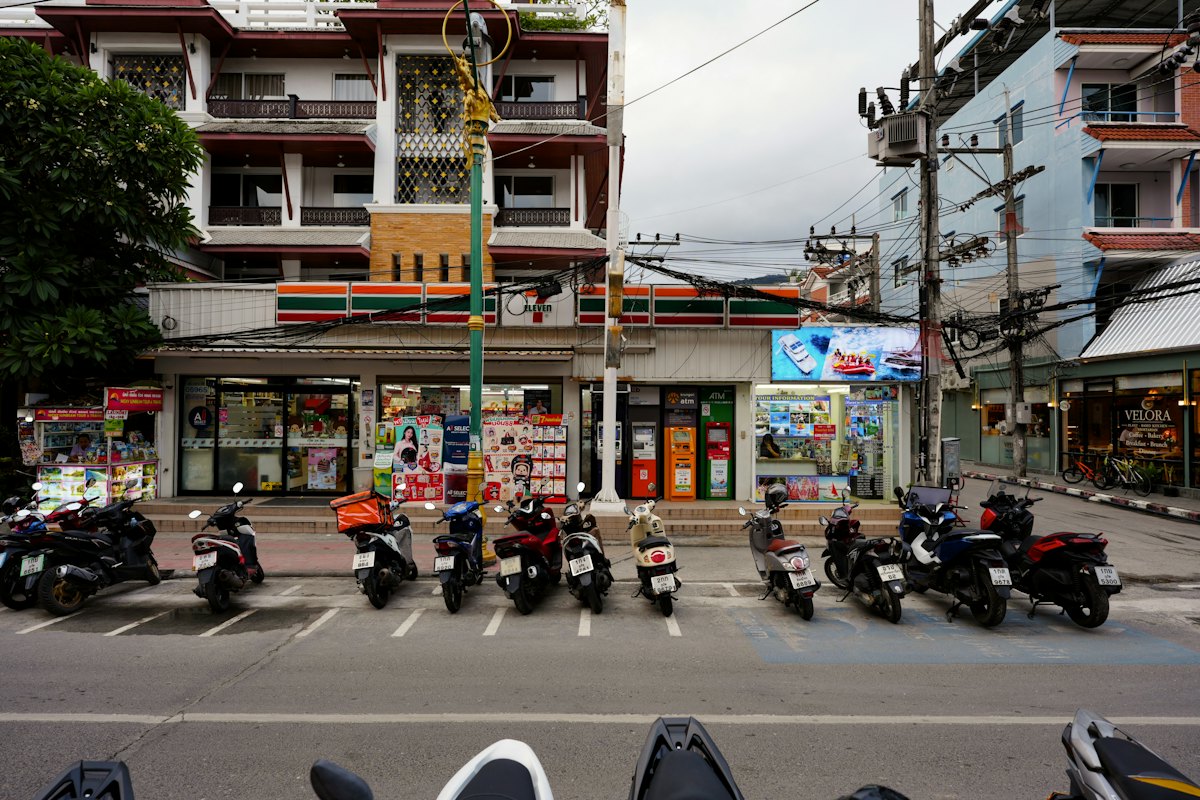 Motorbikes parked outside a 7-Eleven on a street in Thailand