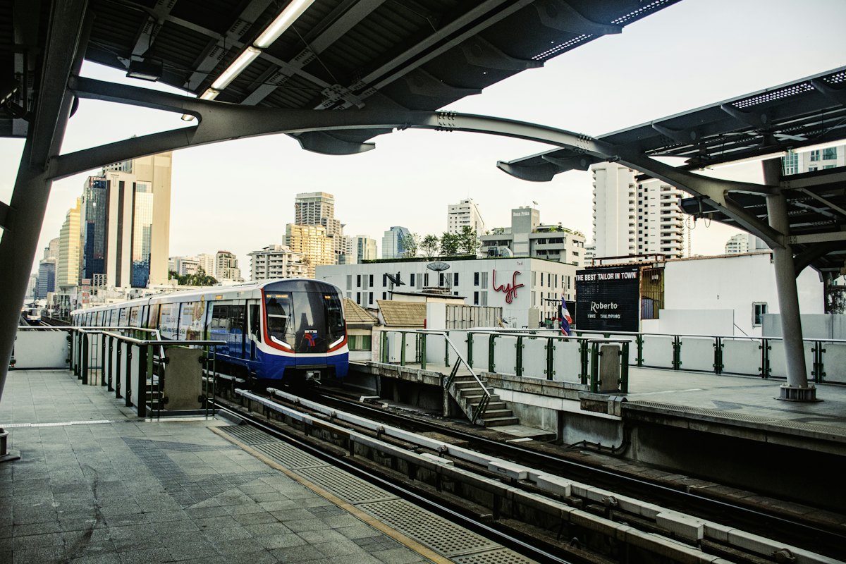 A BTS Skytrain pulling into a covered elevated station in Bangkok
