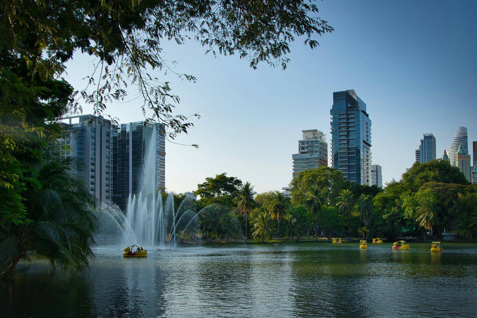 Lumpini Park lake and fountain with Bangkok towers behind