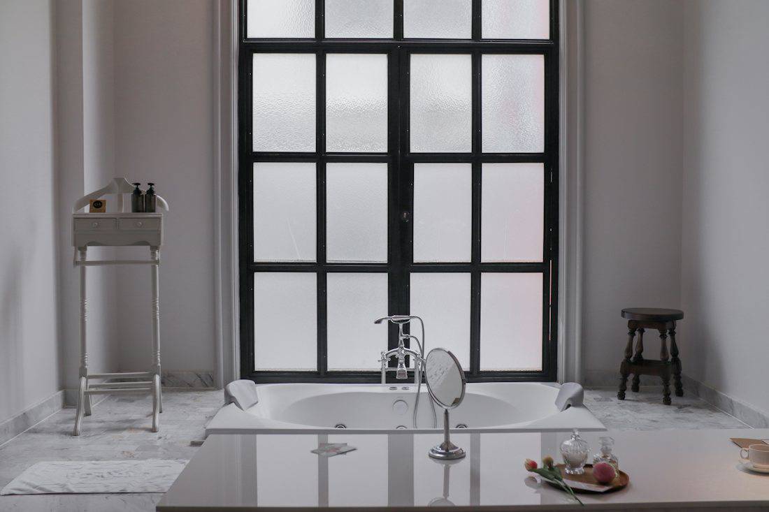 Bright hotel bathroom with a bathtub by the window