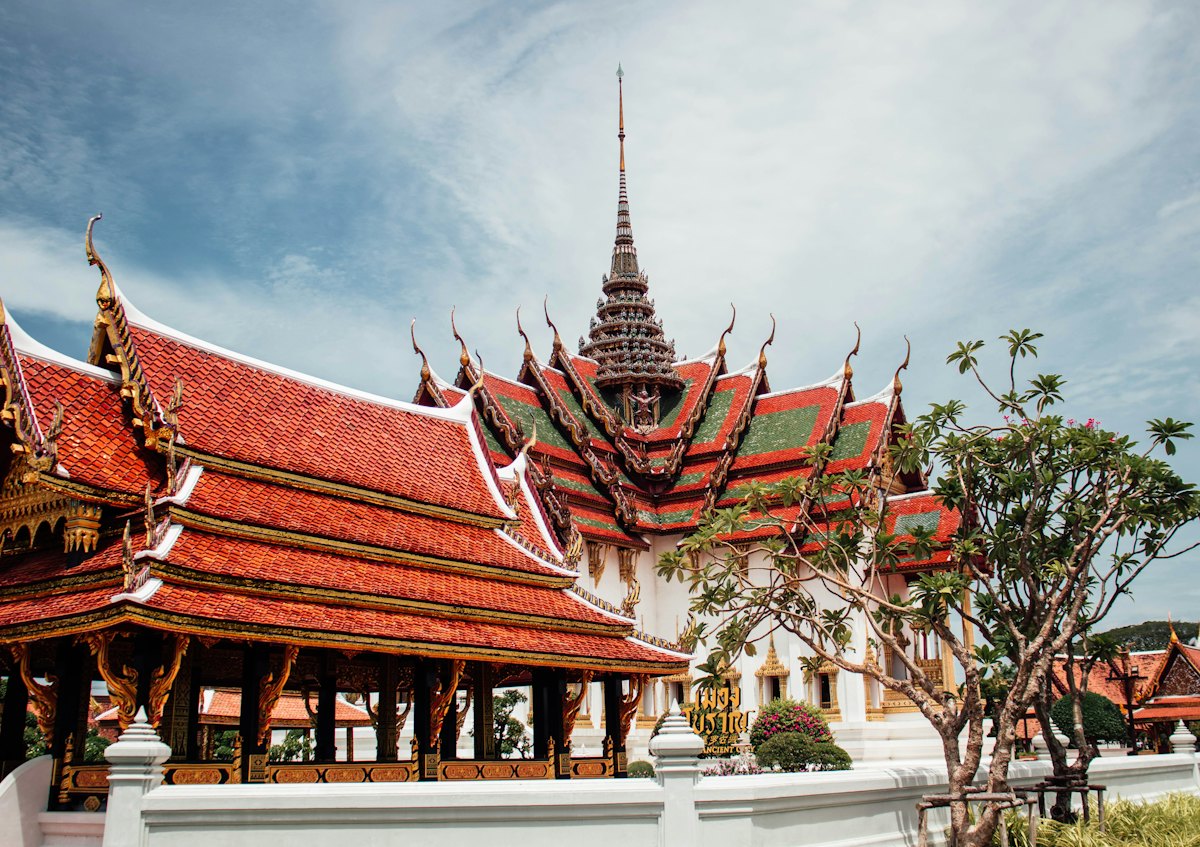 A small temple with tiered red roofs behind a white wall, with no crowds