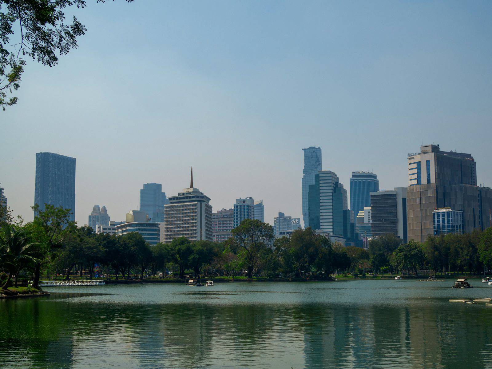 Lumpini Park lake with the Bangkok skyline behind it