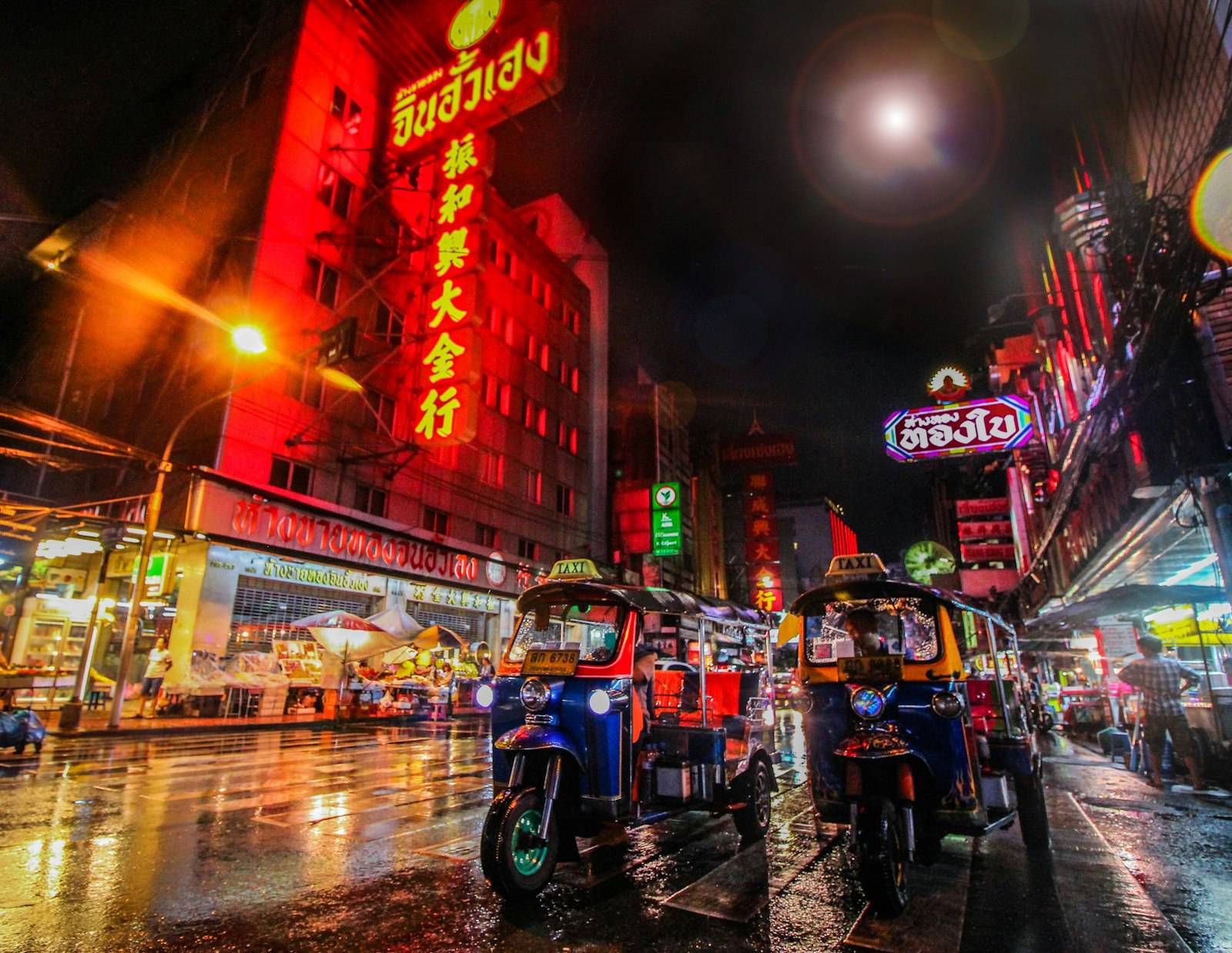 Tuk tuks on a rain-slicked Yaowarat Road at night in Bangkok