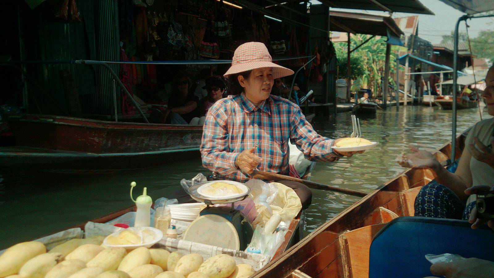 Vendor preparing food on a boat at a Thai floating market