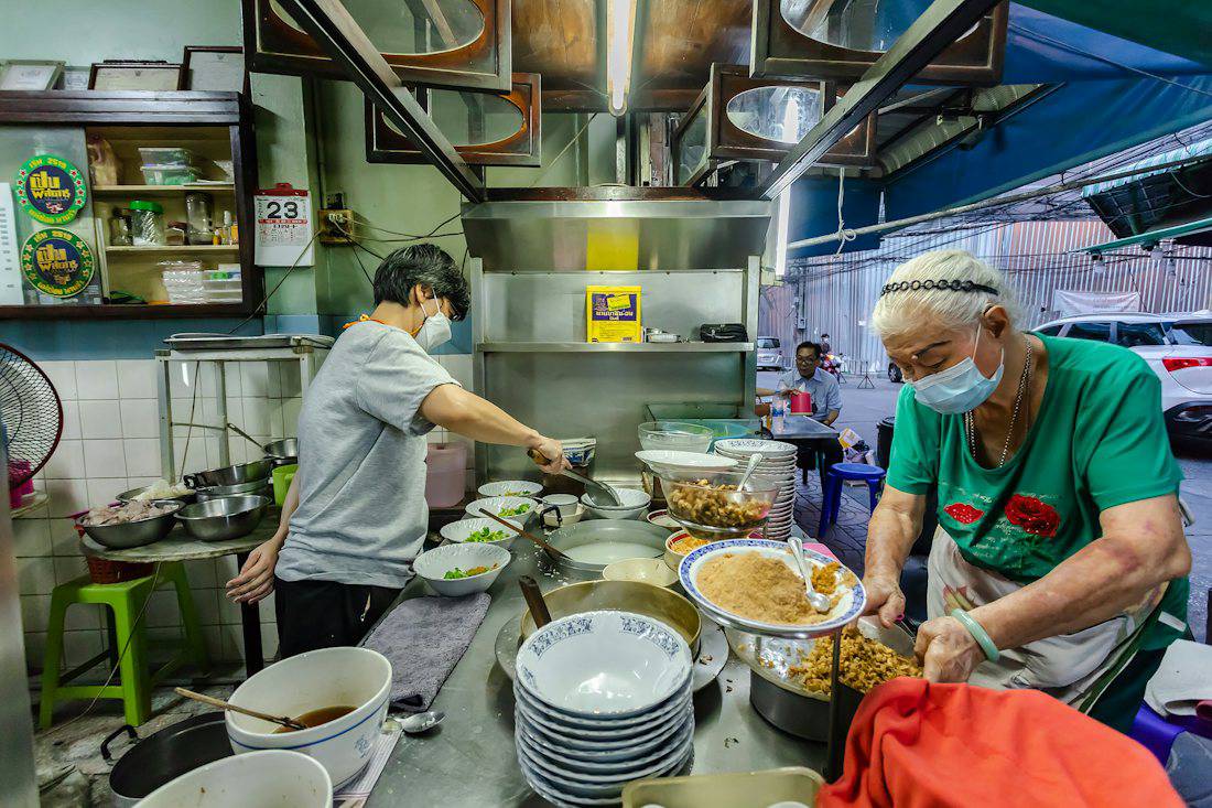 Cooks working in an open kitchen at a Bangkok food stall