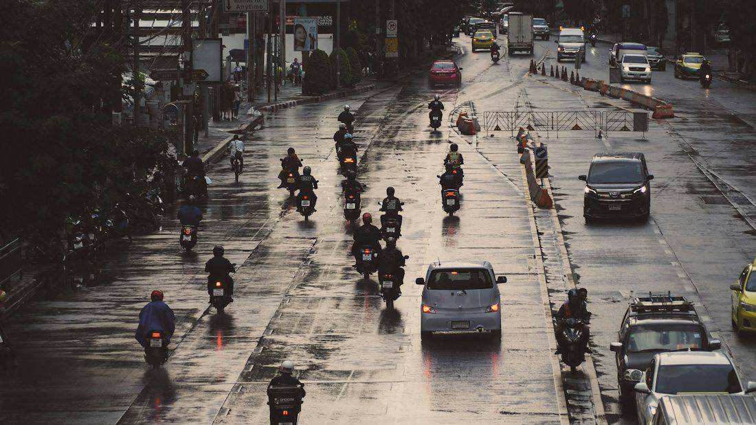 Motorbikes and cars on a wet Bangkok road after rain