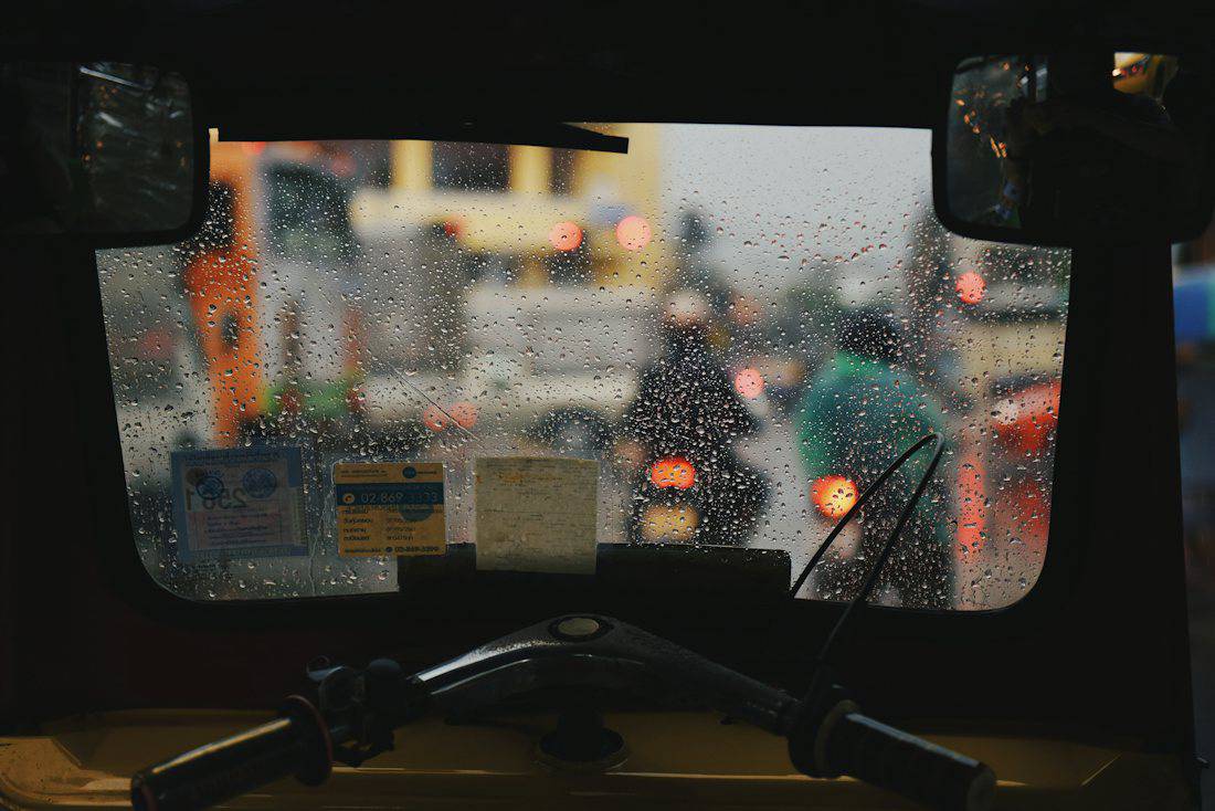 View through a rain-covered tuk tuk windshield in Bangkok