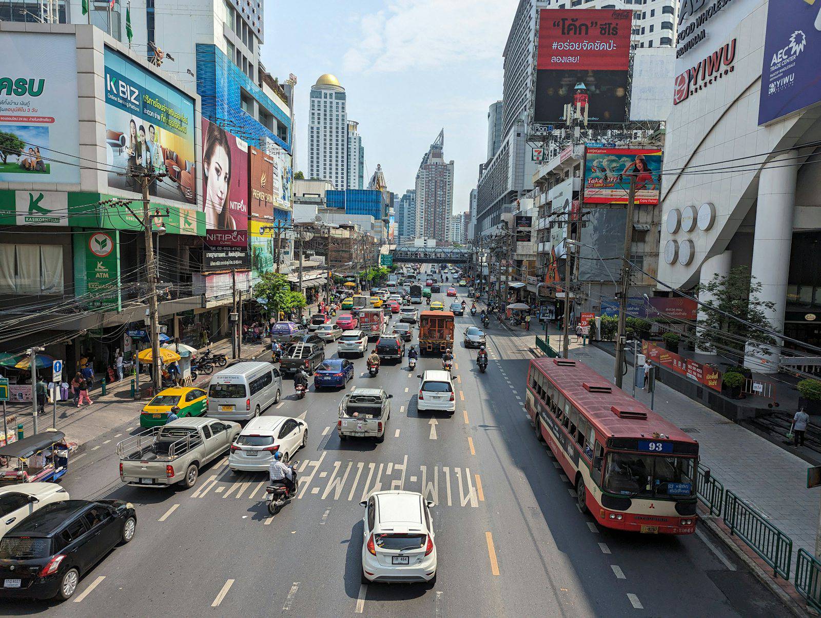 Traffic and shopfronts along a busy road in central Bangkok