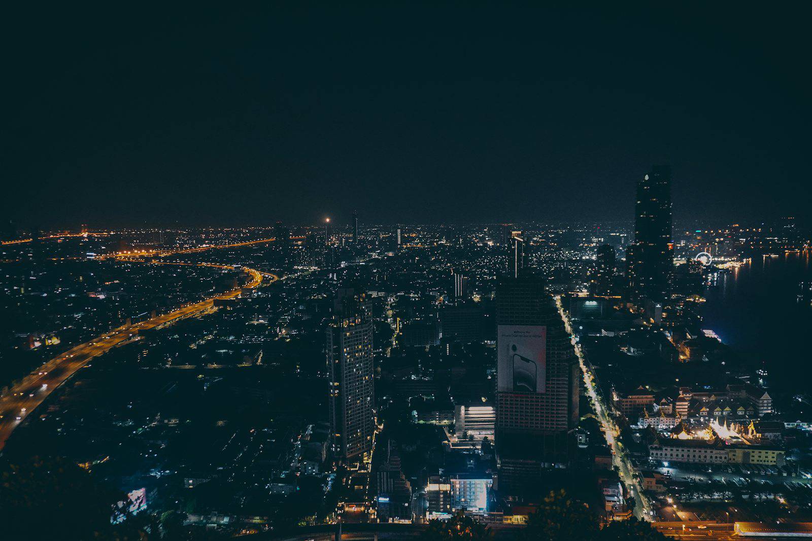 Bangkok skyline glowing over the river at night